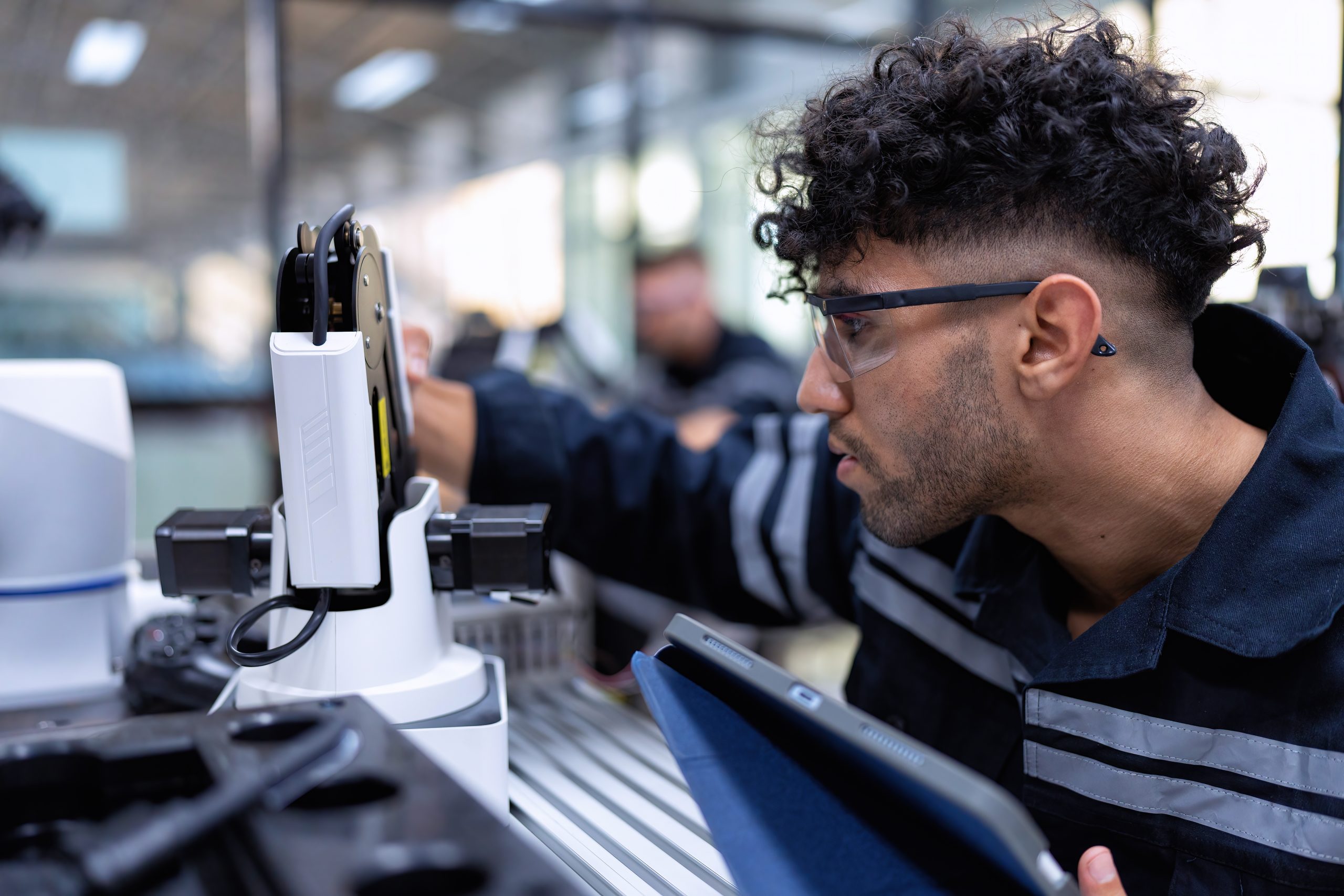 Engineer sitting in robot fab. room use tablet pc quality check robot arm hardware engineering