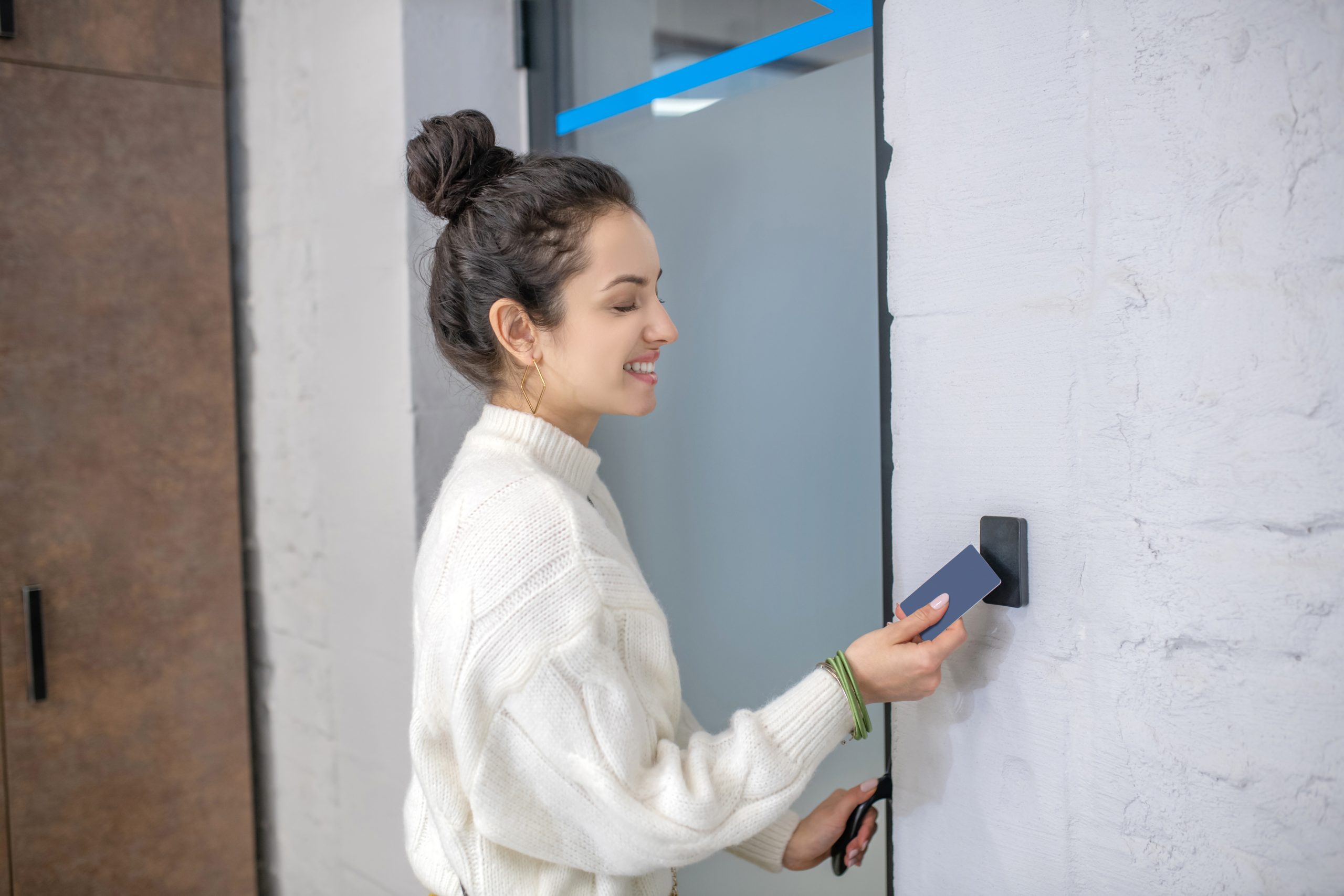 Indoors. Young woman holding access card to unclock the door, smiling